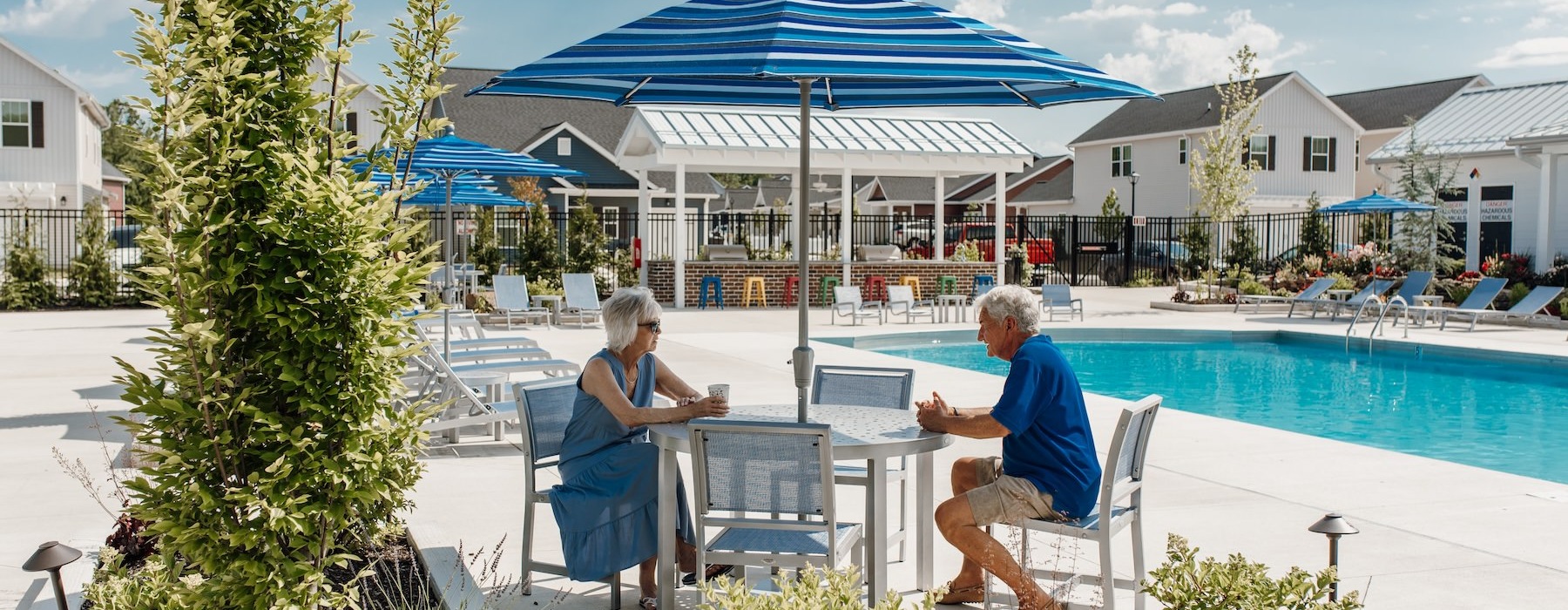 two people sitting pool-side under an umbrella